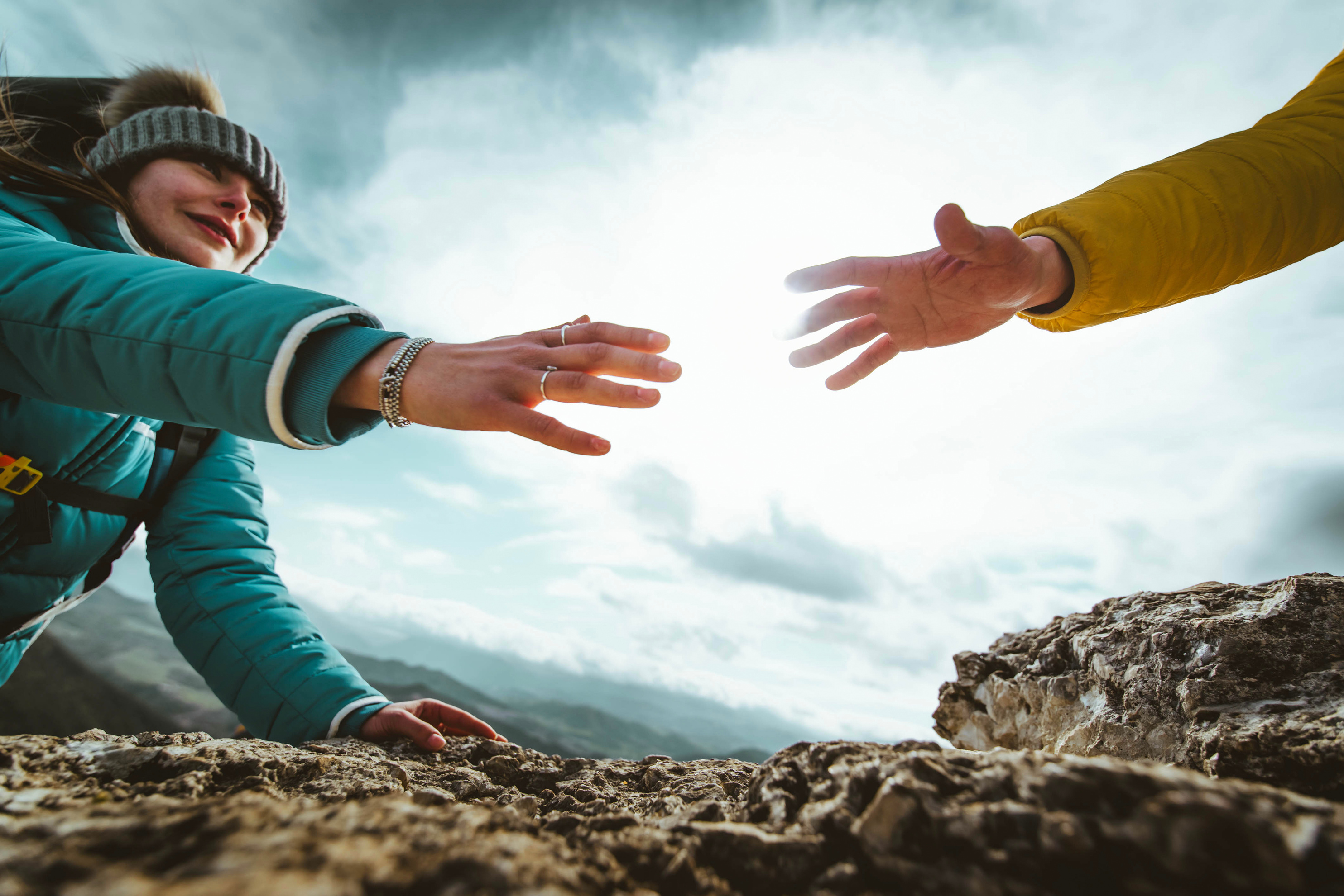 People helping each other hike up a mountain at sunrise - Giving